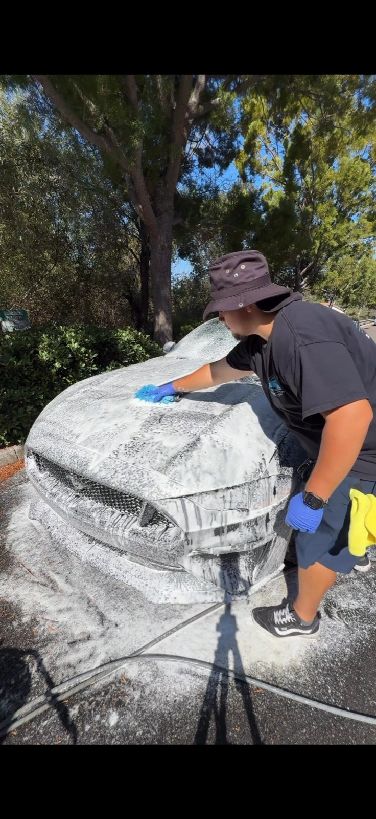 Angel, owner of Reflection Detailing, foam-washing a Mustang in Chula Vista
